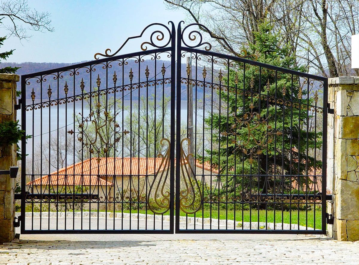 Bronze decorations, including a monogrammed “K” add color contrast to this wrought iron gate.