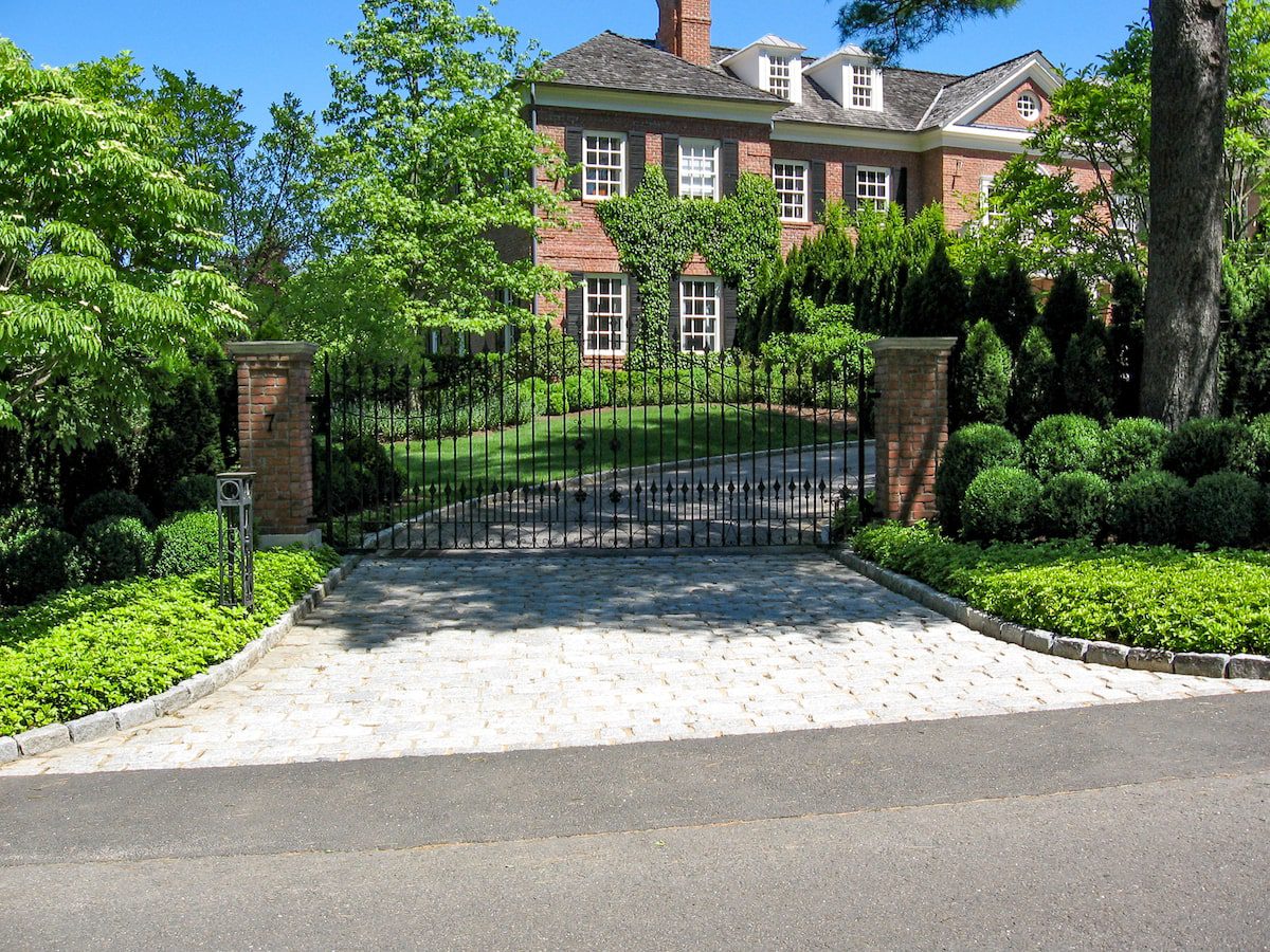 metal driveway gate with brick columns and stone driveway