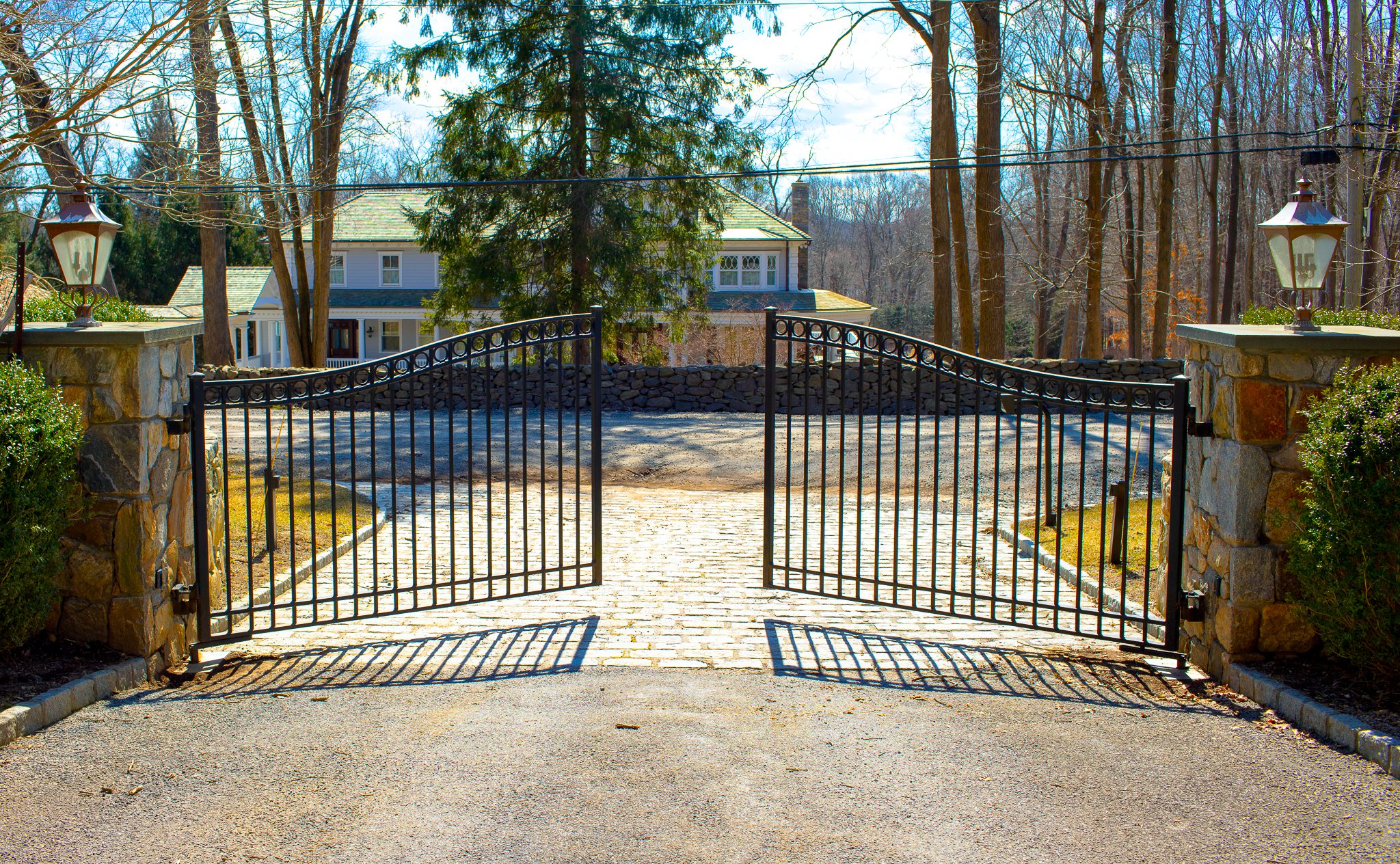 The two wrought iron panels of an automatic driveway gate swing open to allow entry.